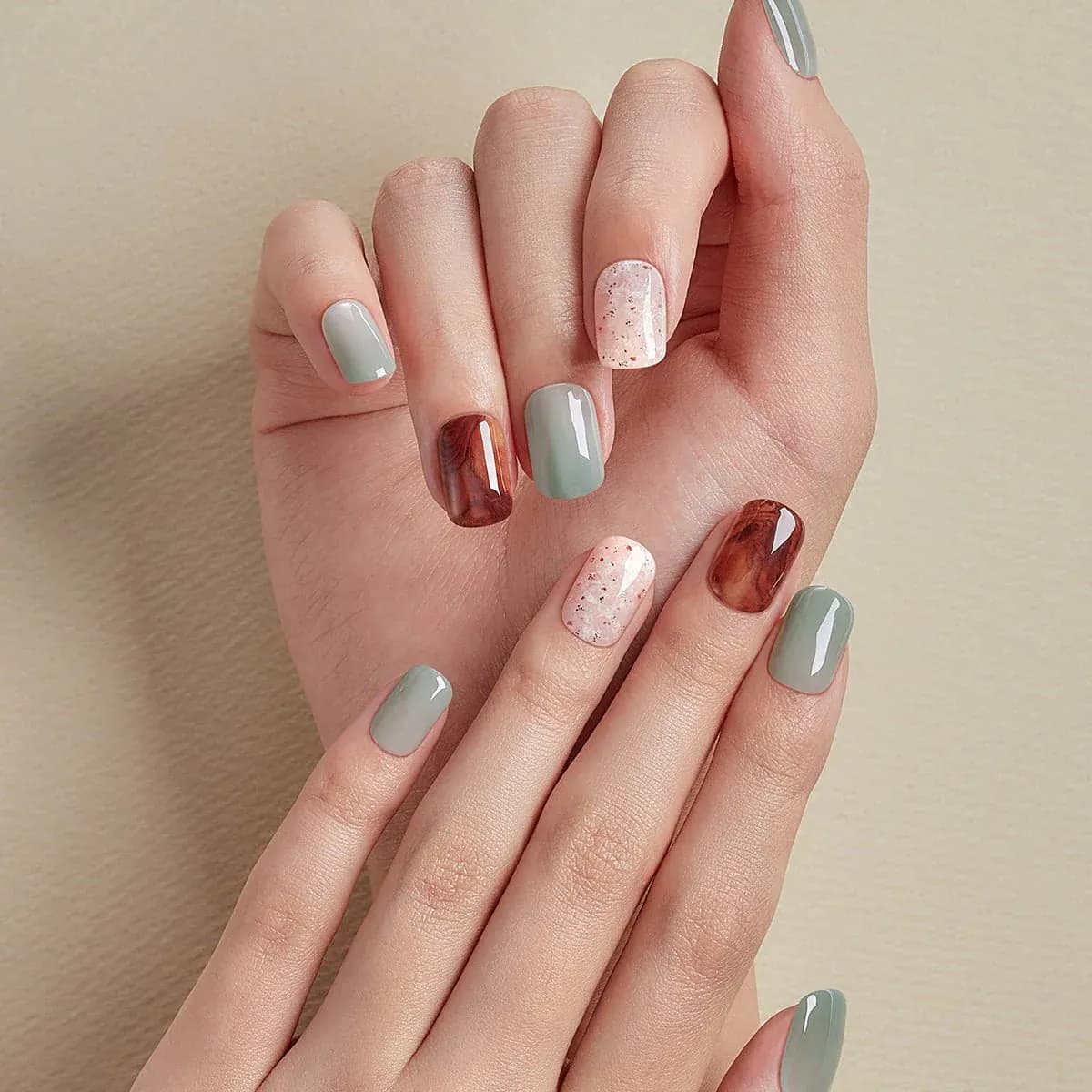 Short nails in mixed sage green, brown, cream and speckled designs