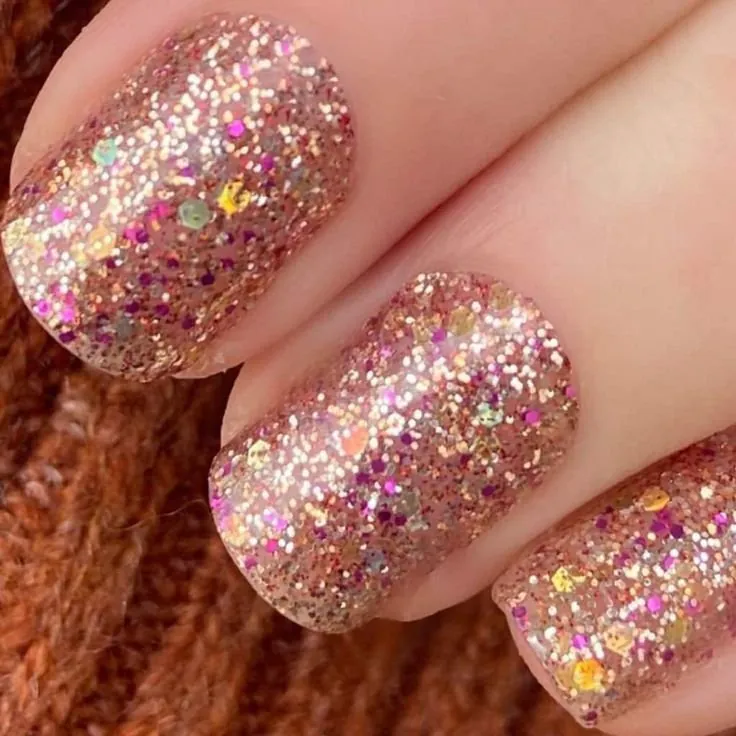 Short square nails covered in rose gold and multicolor glitter