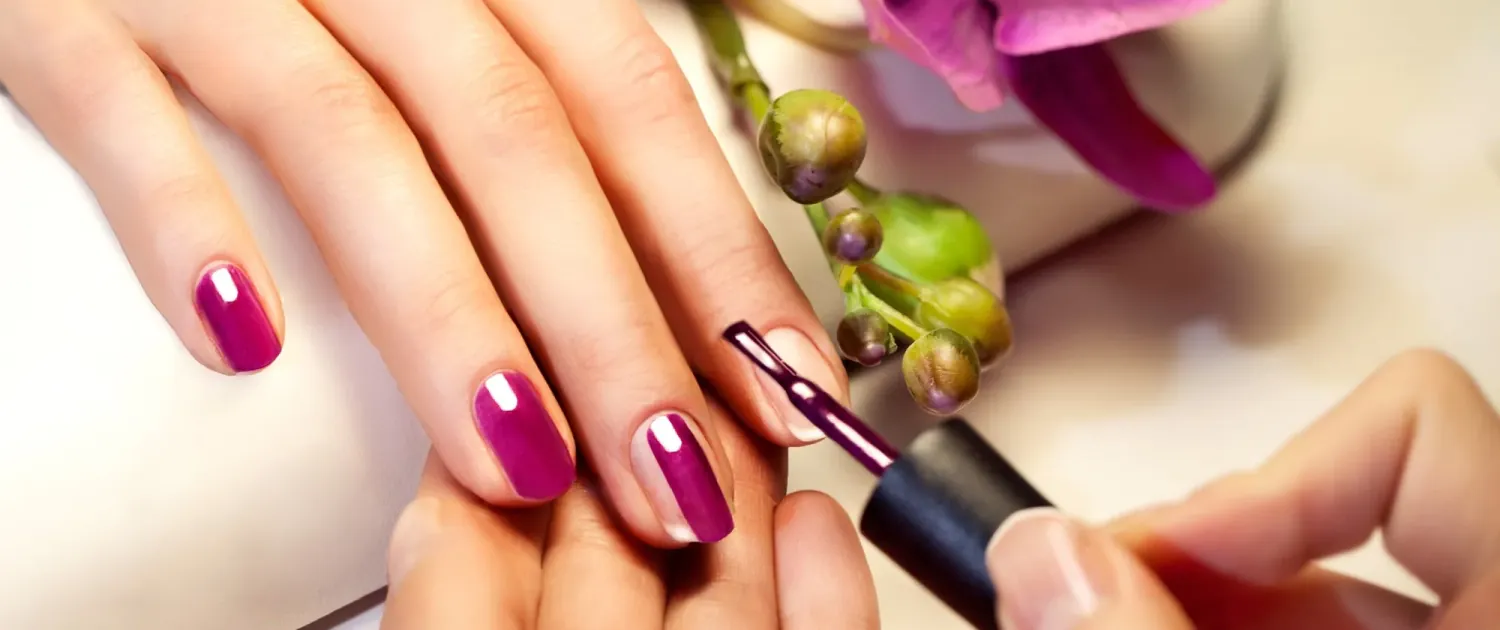 Magenta polish being brushed onto short natural nails